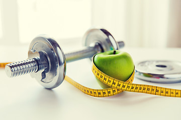 Image showing close up of dumbbell and apple with measuring tape