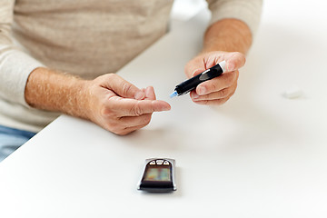 Image showing senior man with glucometer checking blood sugar