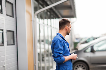 Image showing auto mechanic smoking cigarette at car workshop