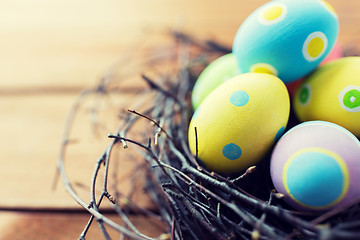 Image showing close up of colored easter eggs in nest on wood