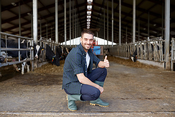 Image showing man or farmer with cows in cowshed on dairy farm