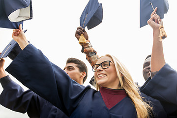 Image showing happy students or bachelors waving mortar boards