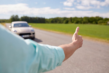 Image showing man hitchhiking and stopping car with thumbs up