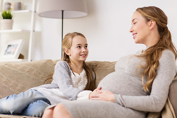 Image showing happy pregnant woman and girl on sofa at home