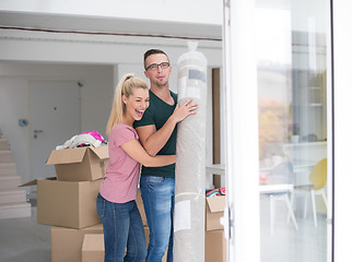 Image showing couple carrying a carpet moving in to new home