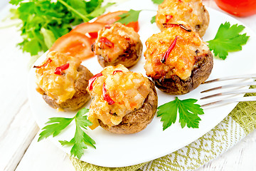 Image showing Champignons stuffed with meat and peppers in plate on light boar