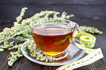 Image showing Tea with wormwood in glass cup and meter on dark board