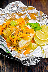 Image showing Pike with leeks and carrots in foil on dark board