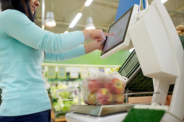 Image showing woman weighing apples on scale at grocery store