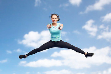 Image showing happy smiling sporty young woman jumping in air