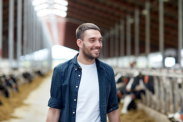 Image showing man or farmer with cows in cowshed on dairy farm