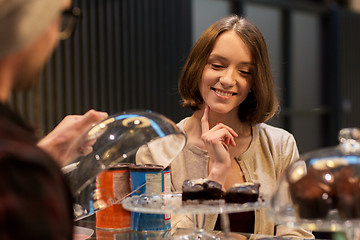 Image showing happy woman choosing cakes at vegan cafe