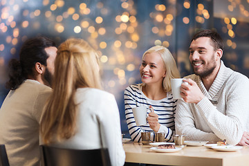 Image showing happy friends drinking tea or coffee at cafe