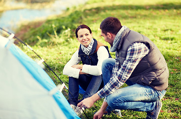 Image showing happy couple setting up tent outdoors