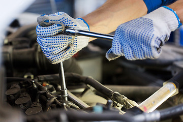 Image showing mechanic man with wrench repairing car at workshop