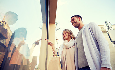 Image showing happy couple with shopping bags at shop window