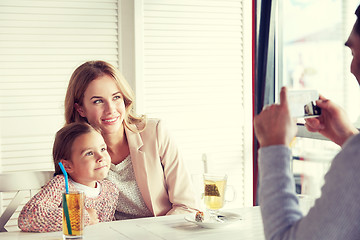 Image showing happy family picturing by smartphone at restaurant