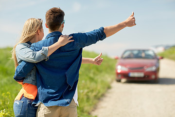 Image showing couple hitchhiking and stopping car on countryside