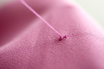 Image showing thread with cross-stitch on pink fabric