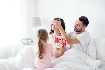 Image showing happy girl giving flowers to mother in bed at home