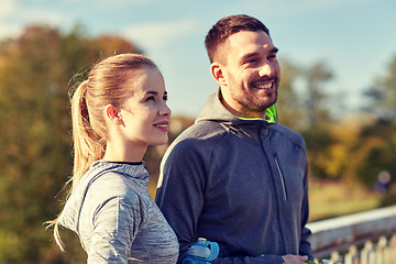 Image showing smiling couple with bottles of water outdoors