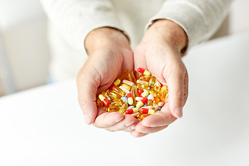 Image showing close up of senior man hands holding pills