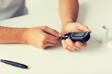 Image showing close up of man checking blood sugar by glucometer