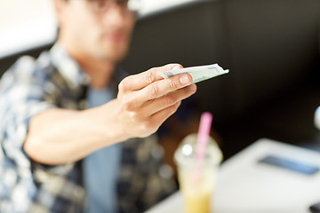 Image showing happy man with cash money paying at cafe