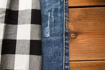 Image showing close up of checkered shirt and jeans on wood