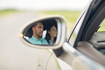 Image showing side mirror reflection of happy couple driving car