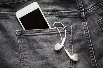 Image showing smartphone and earphones in denim or jeans pocket