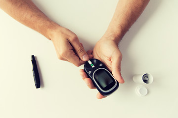 Image showing close up of man checking blood sugar by glucometer