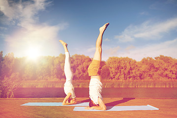 Image showing couple making yoga headstand on mat outdoors