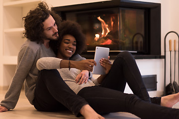 Image showing multiethnic couple used tablet computer on the floor