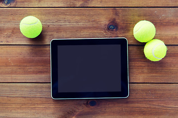 Image showing close up of tennis balls and tablet pc on wood