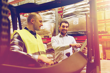 Image showing happy men with tablet pc and forklift at warehouse