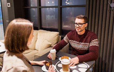 Image showing happy couple with coffee eating cake at cafe