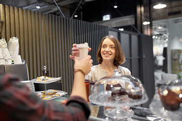 Image showing happy woman taking coffee cup from seller at cafe