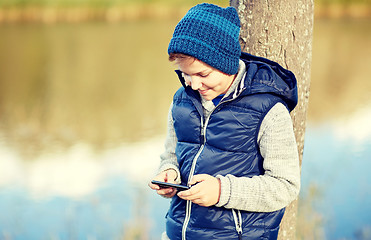 Image showing happy boy playing game on smartphone outdoors