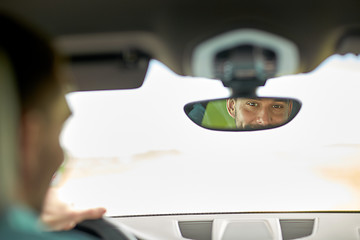 Image showing rearview mirror reflection of man driving car