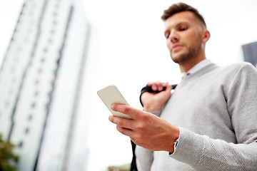 Image showing close up of man texting on smartphone in city