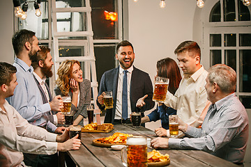 Image showing Group of friends enjoying evening drinks with beer