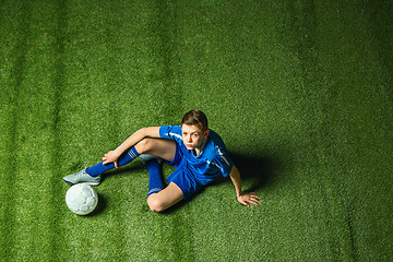 Image showing Boy soccer player sitting on greeb grass