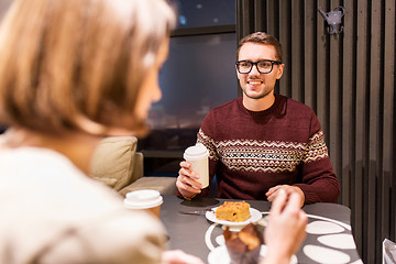 Image showing happy couple with coffee eating cake at cafe