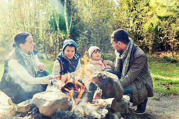 Image showing happy family roasting marshmallow over campfire