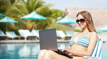 Image showing happy young woman in shades with laptop on beach