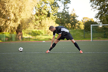 Image showing soccer player stretching leg on field football