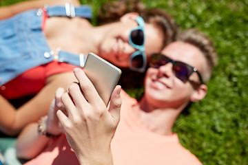 Image showing happy teenage couple smartphone lying on grass