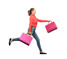 Image showing smiling young woman with shopping bags running