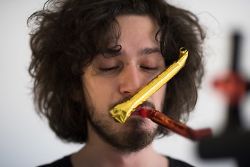 Image showing Portrait of a man in party hat blowing in whistle